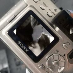 a person holding up a camera with a cat on it's screen and its reflection in the lens