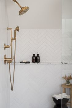 a bathroom with a shower head and two bottles on the shelf in front of it