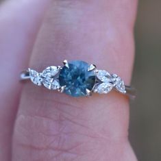 a woman's hand holding a blue and white diamond ring