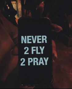 someone holding up a cell phone that says never 2 fly 2 pray