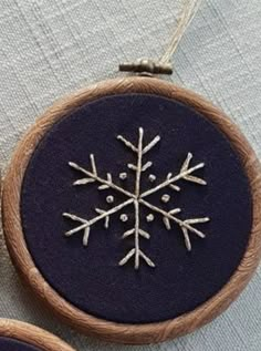 two embroidered snowflakes hanging from wooden hoop