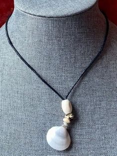 a woman wearing a necklace with two white seashells on it