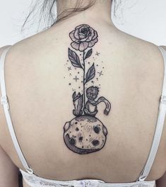 the back of a woman's neck with a flower and cat tattoo on it