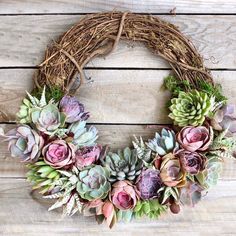 a wreath with succulents and greenery is on a wooden surface, ready to be used as a decoration