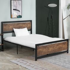 a bed with wooden headboard and foot board, in a room with green walls