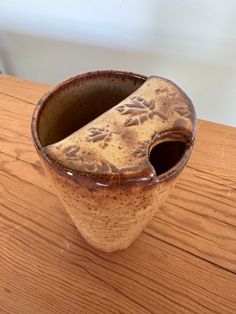 a brown vase sitting on top of a wooden table