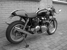 a black motorcycle is parked next to a brick wall and red stand on the sidewalk