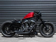 a red and black motorcycle parked in front of a garage door