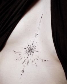 a woman's chest with a dandelion tattoo on her left side breast