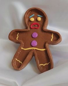 a cookie shaped like a man with buttons on it's face and chest, sitting on a white sheet