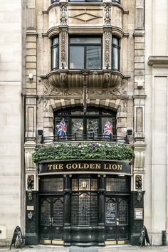 the golden lion pub in london is decorated with flowers and ivy on its front window