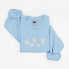 Introducing our Daisies Embroidered Sweatshirt, a delightful addition to your wardrobe that effortlessly combines comfort and style. This 2D Crewneck Sweatshirt is not only a fashion statement but also a thoughtful gift option for your loved ones. With meticulous attention to detail, this sweatshirt is designed to bring joy and warmth to your everyday attire, while showcasing your love for nature and its beautiful creations. Featuring a stunning embroidered daisies design, this sweatshirt immedi Trendy Long Sleeve Top With Embroidered Logo, Casual Long Sleeve T-shirt With Floral Embroidery, Spring Casual Sweatshirt With Embroidered Graphics, Spring White Sweatshirt With Custom Embroidery, Casual Embroidered Sweatshirt For Spring, White Sweatshirt With Custom Embroidery For Spring, White Custom Embroidered Sweatshirt For Spring, Casual Cotton Sweatshirt With Floral Embroidery, Spring Crew Neck Sweatshirt With Embroidered Graphics