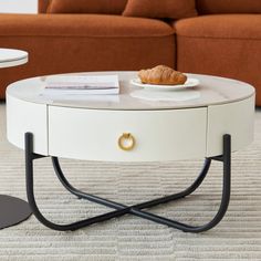 a coffee table with a croissant sitting on it's legs in front of a couch