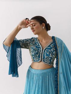 A three-piece Blue Monochrome lehenga set from the Suruchi Parakh collection. This elegant georgette crepe lehenga is paired with a hand-embroidered blouse. The outfit is completed with a matching georgette crepe dupatta. The blouse sleeves have a high low flare. And, the dupatta has a beautiful touch of ruffle and pearl hemline on it. Monochrome Lehenga, Umbrella Sleeves, Tulle Lehenga, Lehenga Blue, Long Skirt Top Designs, Layered Lehenga, Ruffle Dupatta, Hand Embroidered Blouse, Flare Blouse