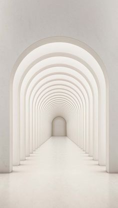 an empty tunnel with white walls and arches leading to the light at the end is seen in this image