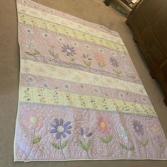 a baby quilt is laying on the floor in front of a dresser and bedding