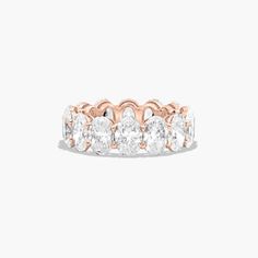 a rose gold ring with five oval cut diamonds on the side and two rows of smaller round