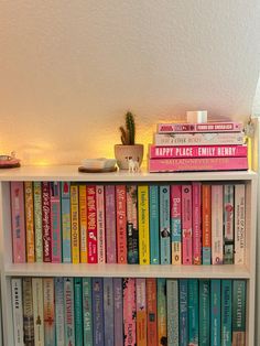 a white book shelf filled with lots of books next to a potted plant on top of it