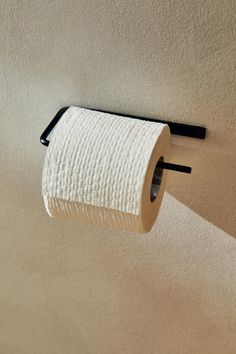 a roll of toilet paper is hanging on the wall next to a black metal holder