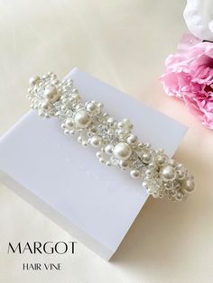 a white card with pearls on it next to pink flowers and peonie blossoms