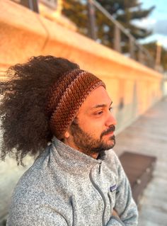 a man with long hair wearing a knitted headband and looking off into the distance