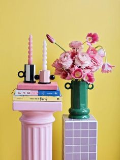 pink flowers are in a green vase next to a stack of books on a table