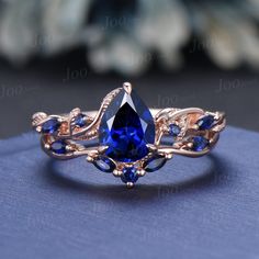 a ring with blue stones and leaves on the side, sitting on top of a cloth