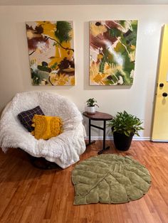 a living room with two paintings on the wall and a chair in front of it