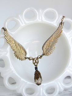 This necklace features two highly-detailed brass angel wings, and a central filigree bead drop. The bead is Czech glass--transparent white with metallic gold flecks. I have hand-patina-ed and distressed the wings with an antiqued white finish. The necklace secures with a lobster clasp. ------------------- **Please be sure to read my shipping and store policies, and don't hesitate to send me a message with any questions you may have! INTERNATIONAL BUYERS: Please be aware that there may be taxes or customs fees that are not included in the purchase price. I cannot reimburse for additional fees. Angel Wings Pendant, Wings Pendant, Glass Transparent, Cardboard Gift Boxes, Angel Wing Pendant, Gold Flecks, Glass Gifts, Fantasy Jewelry, Metallic Gold