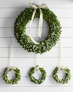 three wreaths hanging on the wall with ribbons