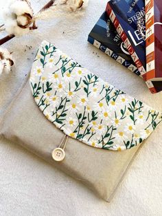 a white flowered purse sitting on top of a table next to books and cotton