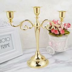 a gold candelabra sitting on top of a white table next to a potted plant