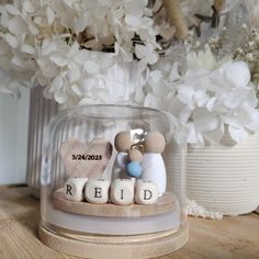 two figurines sitting on top of each other under a glass dome with flowers in the background