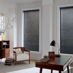 a living room filled with furniture and two windows covered in blind shades next to each other