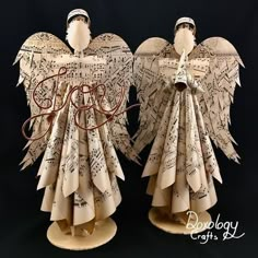 two angel sculptures made out of old sheet music paper with the word love written on them