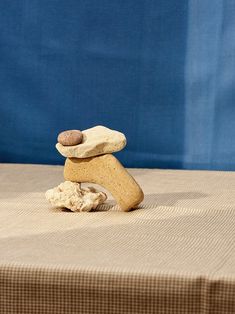 three rocks stacked on top of each other in front of a blue background with a cloth