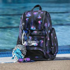 a backpack sitting on the edge of a pool next to a pair of swimming goggles