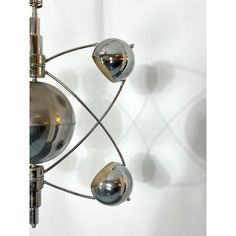 a metal chandelier with three balls hanging from it's sides and two lights on each side