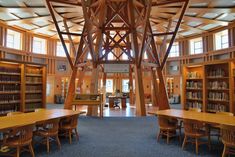 the inside of a library with tables, chairs and bookshelves filled with books