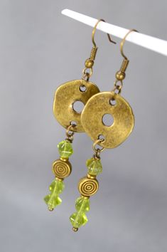 Experience the allure of bohemian elegance with these handmade bronze earrings, intricately adorned with vibrant green Czech glass beads, exclusively designed by Estibela Design. Each earring features a delicate hook base, from which a circular connector gracefully suspends, cascading with rich green bicone beads that create a striking and captivating accent. These earrings, crafted in a bohemian style, seamlessly blend vintage and ethnic elements. They are perfect for those who appreciate uniqu Bohemian Bronze Earrings With Round Beads, Bohemian Bronze Beaded Earrings Nickel Free, Bohemian Bronze Beaded Nickel-free Earrings, Bohemian Brass Jewelry With Large Beads, Gold Bohemian Beaded Earrings, Adjustable Gold Beaded Bohemian Earrings, Bohemian Metal Earrings With Round Beads, Bohemian Czech Glass Earrings For Festivals, Bohemian Jewelry With Decorative Round Beads