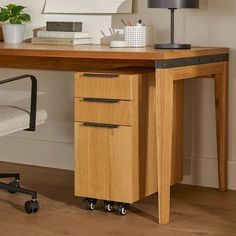 a wooden desk with two drawers and a lamp next to it on top of a hard wood floor