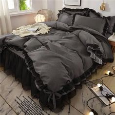 an unmade bed with black ruffled bedspread and lights on the floor