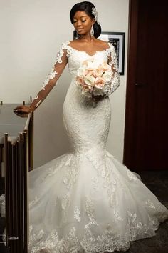 a woman in a wedding dress standing next to a mirror holding a bouquet of flowers