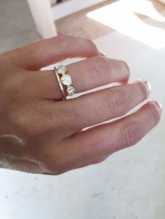 a person's hand holding a ring with three diamonds on it and the middle finger