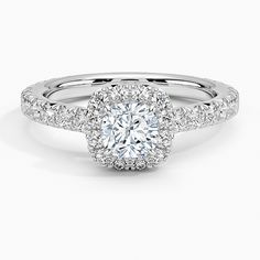 a white gold engagement ring with an oval halo setting and pave set diamonds around the band