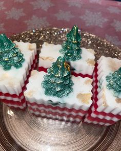 four small christmas trees are on top of some white and red squares with gold trim