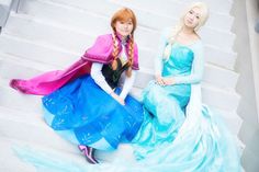 two women dressed as disney princesses sitting on the steps in front of some stairs