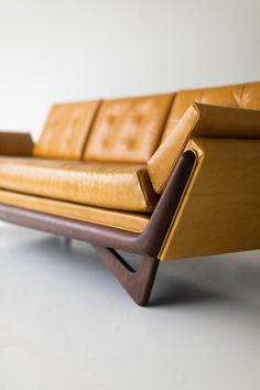 a brown leather couch sitting on top of a white floor next to a wooden frame