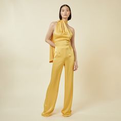 Elevate your style with our chic jumpsuit featuring an elegant draped scarf detail. This modern asymmetrical one-piece with an open back and slightly flared leg offers a sleek and polished look. Perfect for any dressy occasion whilst looking effortlessly sophisticated. Do not wash. Do not bleach. Low Iron. Dry clean only. Chic Formal Satin Jumpsuits And Rompers, Sleek Evening Pantsuit For Spring, Glamorous Satin Jumpsuits And Rompers For Spring, Glamorous Satin Jumpsuits And Rompers For Evening, Elegant Satin Jumpsuits And Rompers For Party, Glamorous Spring Satin Jumpsuit, Chic Sleeveless Satin Jumpsuit, Spring Evening Satin Jumpsuits And Rompers, Spring Evening Jumpsuit With Asymmetrical Neckline