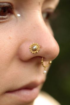 a close up of a person wearing a nose ring with a gold nose pin on it